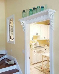 an open door leading to a kitchen with white cabinets and wooden stairs in front of it