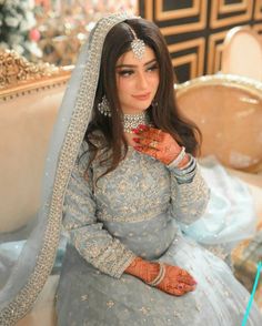 a woman in a blue and white bridal gown sitting on a couch with her hands painted