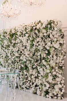 white flowers are growing on the wall next to a glass table and chandelier