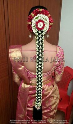 the back of a woman's head with flowers in her hair and an elaborate braid