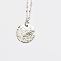 This silver moon pendant features a solid sterling silver disc that I texture with a hammer giving each one a unique pattern. The texture gives a really interesting moonscape effect with a rough stone imprint and rounded dimple pattern. It is the perfect pendant for layering with other simple jewellery for a minimal, modern look. The disc measures around 15mm diameter and the sterling silver chain comes in a choice of lengths. I textured it by hammering it on a rough stone to create irregular im Sterling Silver Etched Round Disc Necklace, Etched Sterling Silver Round Disc Jewelry, Etched Sterling Silver Round Necklace, Hammered Sterling Silver Round Pendant Jewelry, Minimalist Etched Round Pendant Jewelry, Minimalist Etched Round Pendant Necklace, Hammered Sterling Silver Round Pendant, Sterling Silver Round Disc Coin Pendant, Hammered Round Coin Necklace