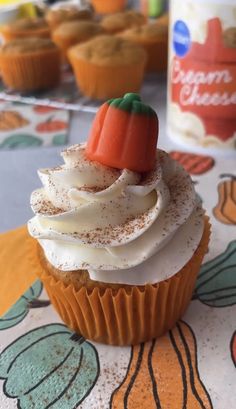 a cupcake with white frosting and a red pepper sitting on top of it