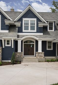 a large blue house with white trim and two garage doors on the front door is shown