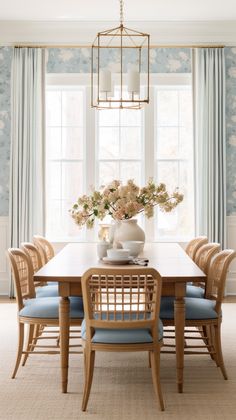 a dining room table with blue chairs and flowers