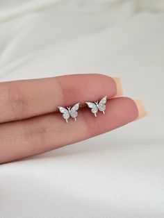 These stunning sterling silver butterfly earring studs will make you stand out from the crowd in all the right ways! They feature a beautiful minimalist design, making them the perfect accessory to add a touch of sophistication to any ensemble. Treat yourself or someone else to these exquisite sterling silver butterfly earring studs to add a stylish flourish to any look. Material: solid sterling silver, cubic zirconia,  Finish: Platinum, or gold plated over sterling silver. Size: 9mm Sold as a p Aesthetic Earrings Studs, White Gold Butterfly Earrings For Pierced Ears, White Butterfly Cubic Zirconia Earrings, Butterfly Shaped White Cubic Zirconia Earrings, White Butterfly-shaped Cubic Zirconia Earrings, Silver Dainty Butterfly Earrings, Dainty Silver Butterfly Earrings, Silver Butterfly Charm Earrings For Anniversary, Silver Cubic Zirconia Butterfly Earrings