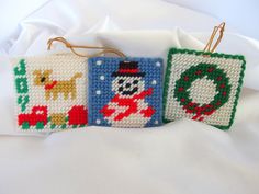 two cross stitch christmas ornaments on a white sheet