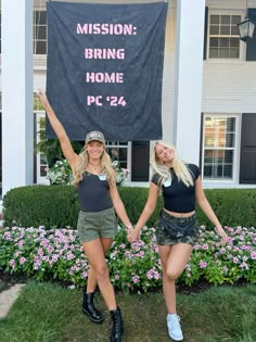 two young women holding hands in front of a house with a banner behind them that says, mission bring home pc 24