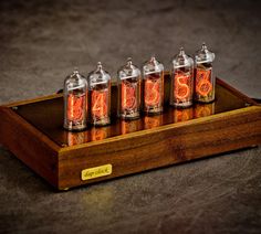 four miniature spice jars sitting on top of a wooden tray