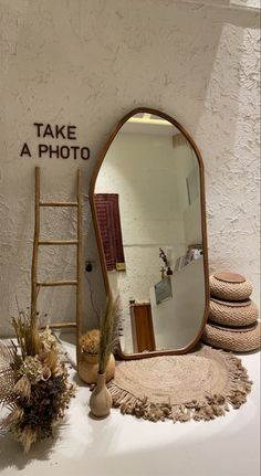 there is a large mirror on the table next to a ladder and vases with flowers