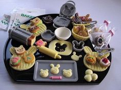 a black tray with various toy food items on top of it, including cookies and pastries