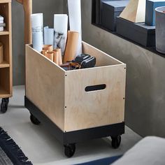 a wooden box filled with lots of different items on top of a floor next to a mirror