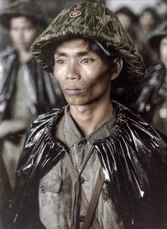 an old photo of a woman wearing a hat and raincoat with other people in the background