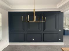 an empty room with black cabinets and a gold chandelier