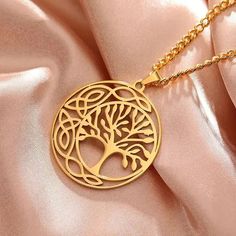 a gold tree of life pendant on a pink satin background with the word love written below it