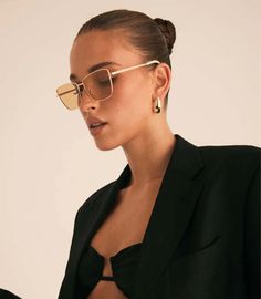 a woman in a black suit and gold sunglasses