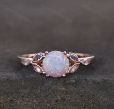 a white opal ring with leaves on the sides and an oval shaped stone in the middle