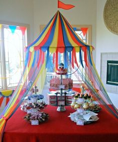 a table topped with cakes and desserts under a colorful canopy