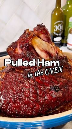 pulled ham in the oven on a blue plate with wine bottles behind it and an advertisement that reads pulled ham in the oven