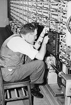 a man working on an electrical panel in a room full of wires and other equipment