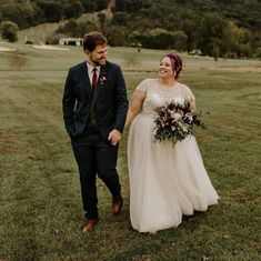 a bride and groom walking through the grass