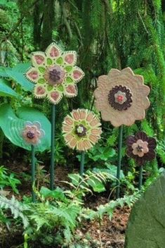 some very pretty flowers in the grass by some rocks and plants with leaves on them