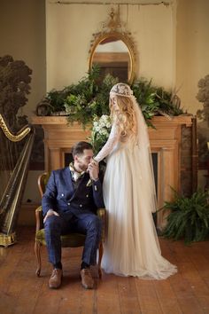 a man kneeling down next to a woman in a wedding dress and holding her hand