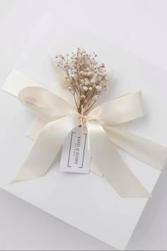 a bouquet of dried flowers tied to a white gift box with a tag on it