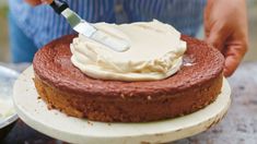 a person spreading icing on top of a cake