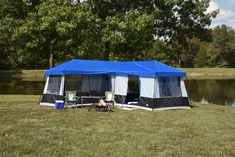 a tent is set up in the grass near a lake