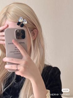 a woman holding up her cell phone to take a selfie in front of her face