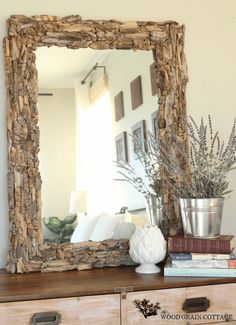 a mirror sitting on top of a dresser next to a vase with flowers in it