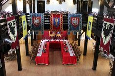 a room filled with lots of tables covered in red and white table cloths next to flags