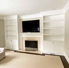 an empty living room with a fireplace and built - in bookshelves