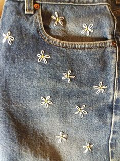 a pair of blue jeans with white flowers on the bottom and yellow dots on the side