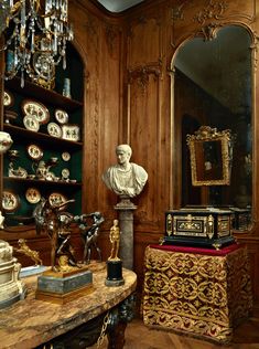 a room filled with lots of gold and white items on top of a wooden table