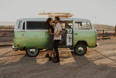 two people standing in front of a green van