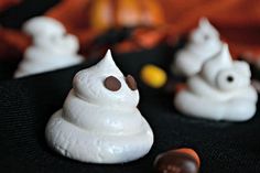 some white frosted treats are sitting on a black tablecloth with orange and yellow candies