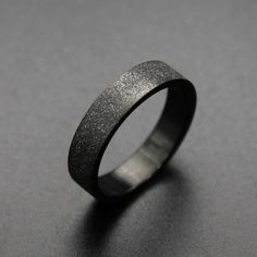 a black ring with silver flecks on the outside and inside, sitting on a gray surface