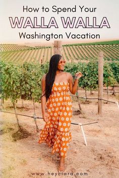 a woman in an orange and white polka dot dress walking through a vineyard