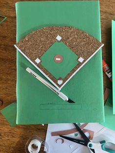 a baseball field made out of green paper and some crafting supplies on a table