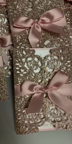 several pink and gold wedding cards with bows on the front, two are folded in half