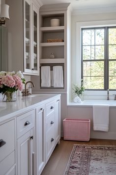 a bath room with a tub a window and a rug on the floor in front of it