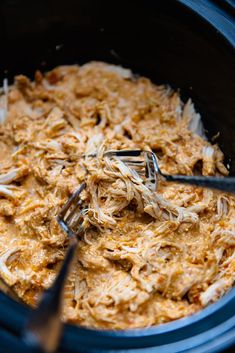 a crock pot filled with shredded meat and a fork