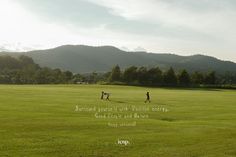 two people walking across a lush green field with mountains in the background and a quote written on it