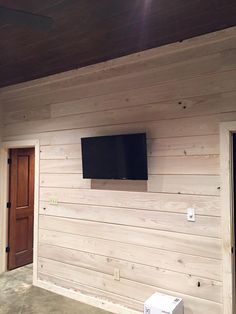 a television mounted to the side of a wooden wall in a room that is being built