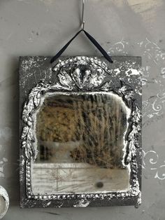 an old mirror hanging on a wall with a black and white border around the frame