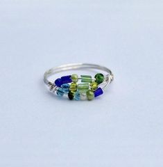 a silver ring with multicolored beads on the inside and outside, sitting on a white surface