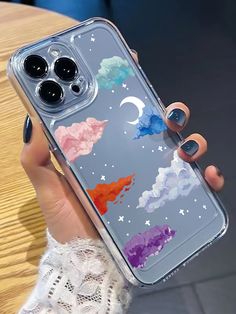 a woman holding up her phone case with an image of clouds and stars on it