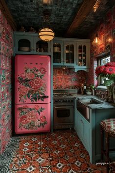 a pink refrigerator in a kitchen with red flowers on the wall and floor tiles covering the walls