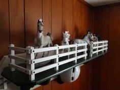 some fake horses are sitting on top of a shelf